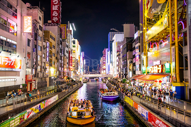 Canal Dotonbori de noche con letreros de neón reflejados en el agua