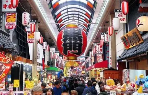 Interior del mercado Kuromon Ichiba con puestos de marisco fresco y visitantes comiendo