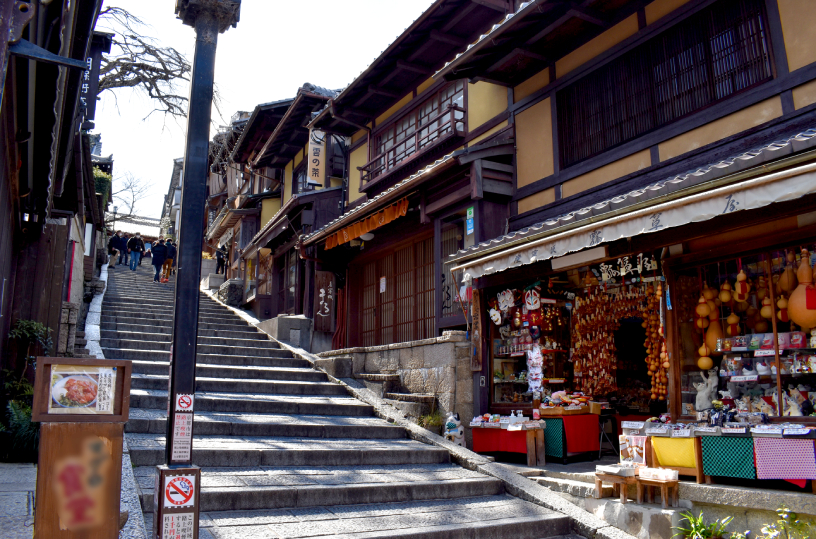 Escaleras de Ninen-zaka en Kioto con puestos de comida y visitantes con kimono